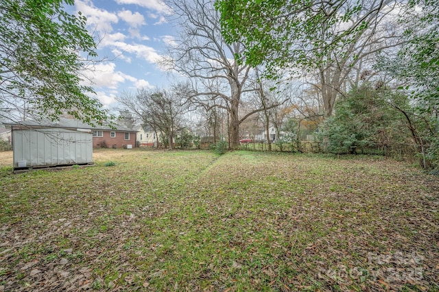 view of yard featuring a shed, fence, and an outbuilding