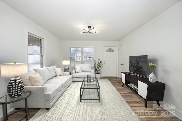 living room featuring a chandelier, baseboards, and wood finished floors