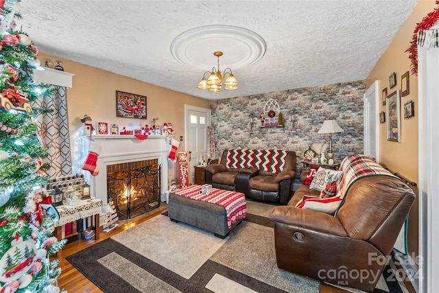 living room featuring a brick fireplace, an inviting chandelier, a textured ceiling, and hardwood / wood-style flooring