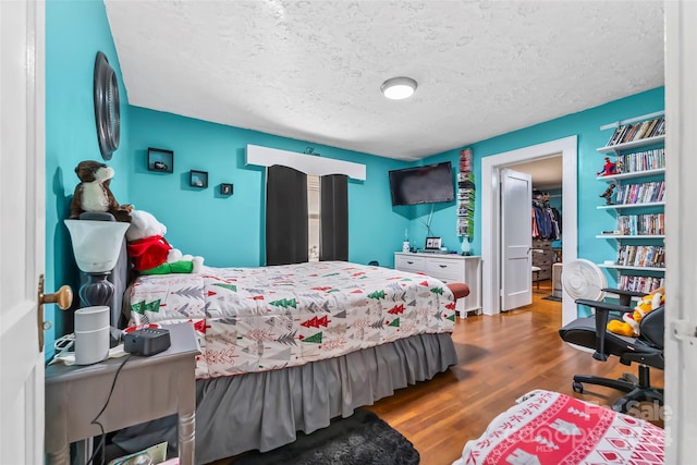 bedroom with a textured ceiling, hardwood / wood-style flooring, a spacious closet, and a closet