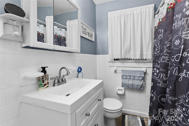 bathroom with vanity, toilet, and tile walls