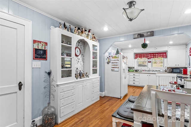 kitchen with sink, white fridge with ice dispenser, light hardwood / wood-style flooring, crown molding, and white cabinets