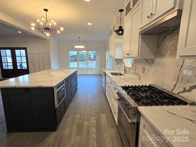 kitchen with a kitchen island, appliances with stainless steel finishes, pendant lighting, white cabinetry, and sink