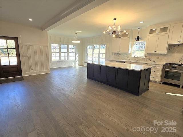 kitchen with a kitchen island, decorative light fixtures, white cabinets, dark hardwood / wood-style flooring, and stainless steel range