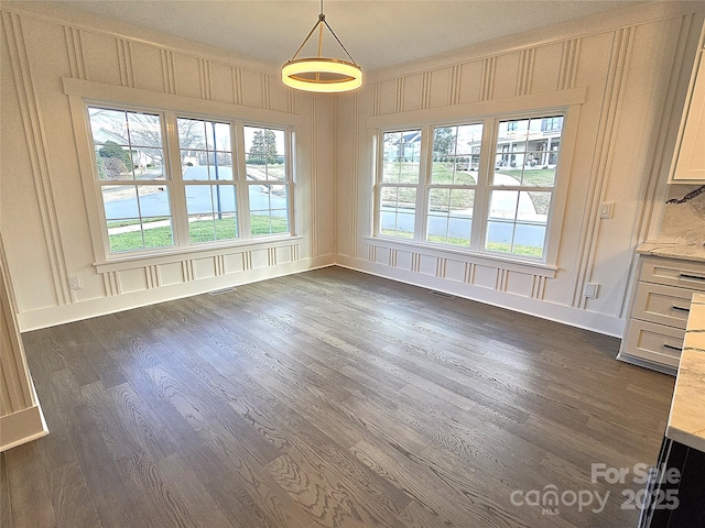 unfurnished dining area with plenty of natural light and dark hardwood / wood-style floors