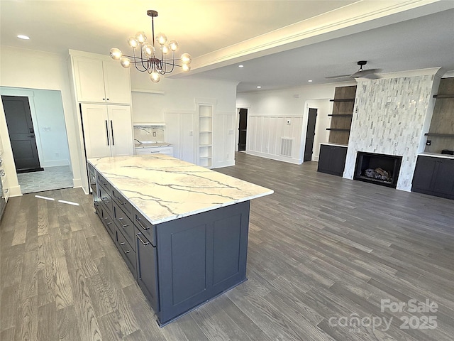 kitchen featuring white cabinetry, decorative light fixtures, ornamental molding, a fireplace, and ceiling fan with notable chandelier