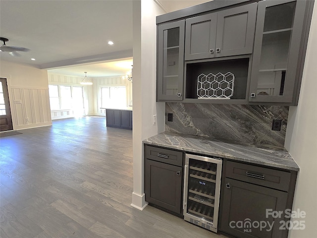 bar featuring light hardwood / wood-style flooring, ceiling fan, light stone counters, decorative backsplash, and beverage cooler