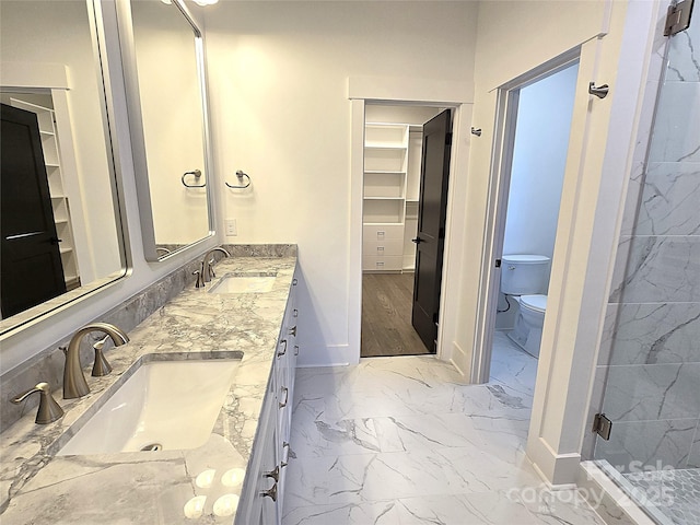 bathroom featuring a shower with door, vanity, and toilet