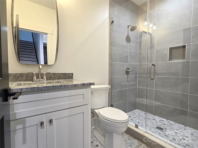 bathroom featuring tile patterned flooring, vanity, a shower with door, and toilet