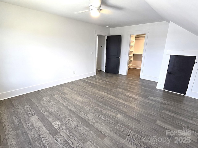 unfurnished bedroom featuring a spacious closet, vaulted ceiling, dark hardwood / wood-style floors, a closet, and ceiling fan