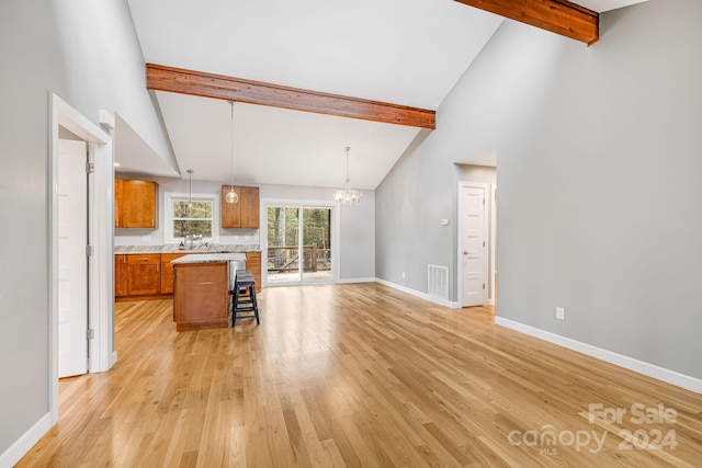 kitchen with a center island, hanging light fixtures, light wood-type flooring, beam ceiling, and a breakfast bar area