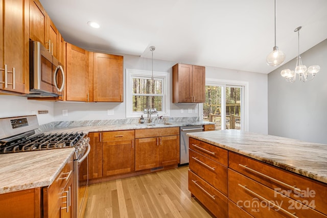 kitchen with light stone counters, sink, light hardwood / wood-style floors, and appliances with stainless steel finishes