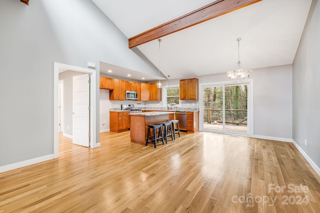 kitchen featuring a center island, pendant lighting, a kitchen bar, appliances with stainless steel finishes, and light wood-type flooring