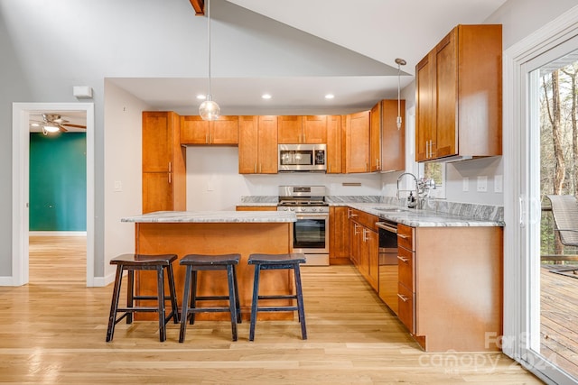 kitchen with a center island, sink, vaulted ceiling, appliances with stainless steel finishes, and light hardwood / wood-style floors