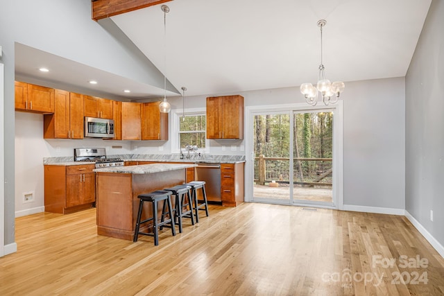 kitchen featuring a breakfast bar area, a center island, stainless steel appliances, and decorative light fixtures