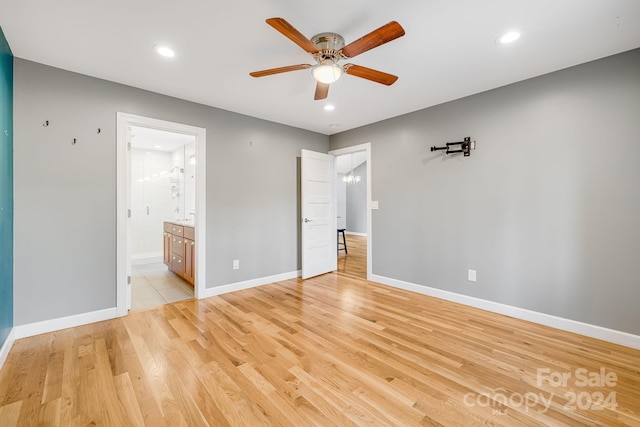 unfurnished bedroom with ensuite bath, ceiling fan, and light wood-type flooring