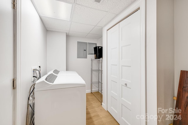 washroom featuring electric panel, light hardwood / wood-style flooring, and washer and clothes dryer