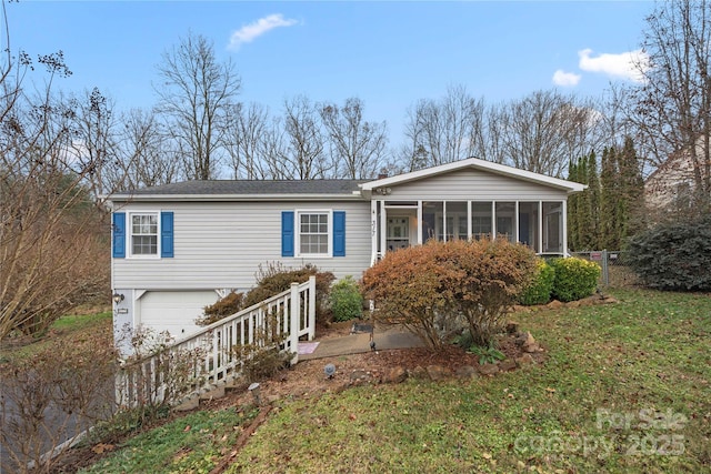 view of front of home with a sunroom, a front yard, and a garage