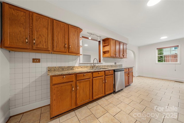 kitchen featuring dishwasher, sink, light stone counters, backsplash, and light tile patterned floors