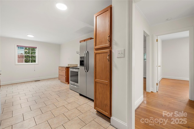 kitchen featuring light tile patterned floors, ornamental molding, and appliances with stainless steel finishes