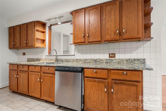 kitchen with backsplash, track lighting, sink, stainless steel dishwasher, and light stone countertops