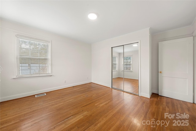 unfurnished bedroom featuring a closet and hardwood / wood-style floors