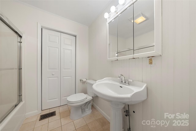 bathroom with tile patterned flooring, toilet, and shower / bath combination with glass door