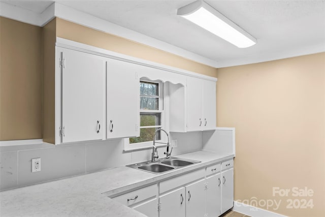 kitchen featuring backsplash, sink, and white cabinets