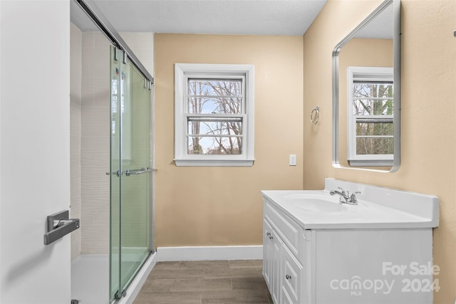 bathroom with a shower with shower door, wood-type flooring, and vanity