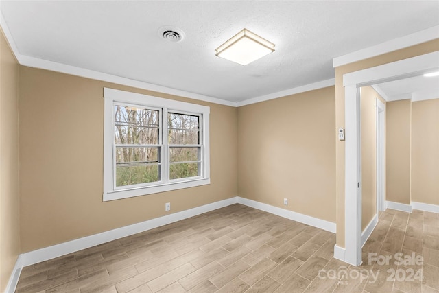 spare room with a textured ceiling, light hardwood / wood-style floors, and crown molding