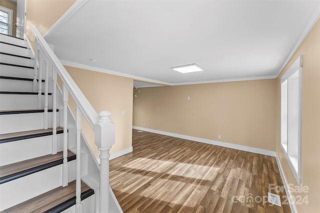 stairs featuring hardwood / wood-style flooring, a healthy amount of sunlight, and crown molding