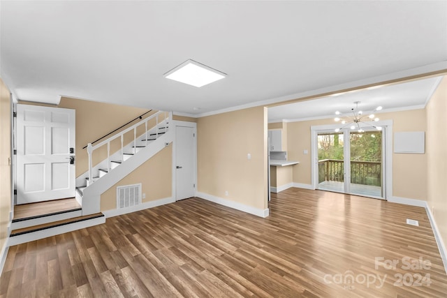 unfurnished living room featuring hardwood / wood-style flooring, a notable chandelier, and ornamental molding