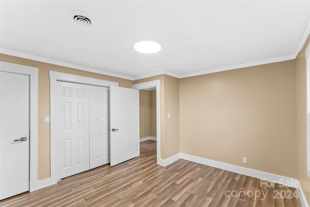 unfurnished bedroom with crown molding, a closet, and light hardwood / wood-style floors