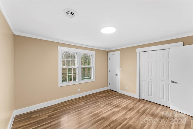 unfurnished bedroom with hardwood / wood-style flooring, crown molding, and a closet