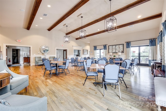 dining area with beamed ceiling, an inviting chandelier, high vaulted ceiling, and light hardwood / wood-style flooring