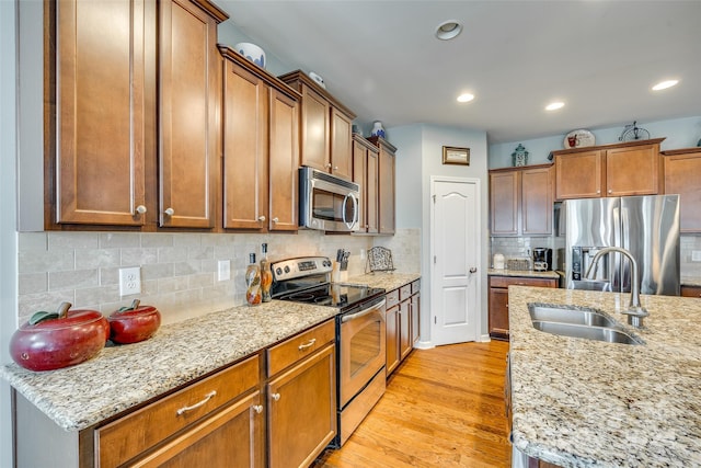 kitchen featuring light stone countertops, appliances with stainless steel finishes, and light wood-type flooring