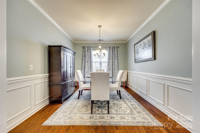 dining area with a chandelier, a decorative wall, dark wood-type flooring, and ornamental molding