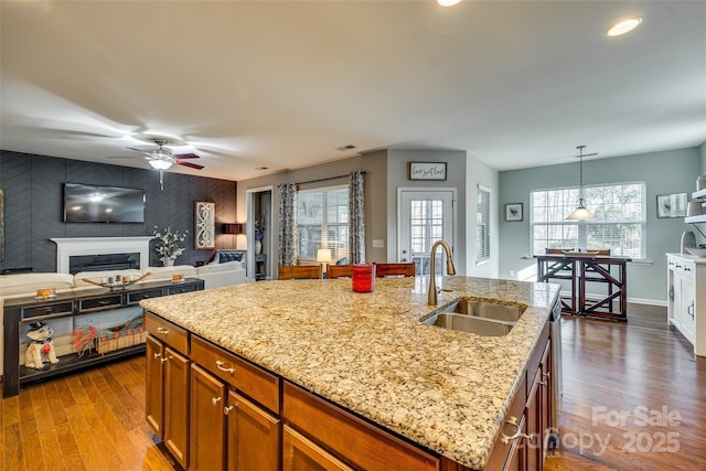 kitchen with an accent wall, dark wood-style flooring, a fireplace, and a sink