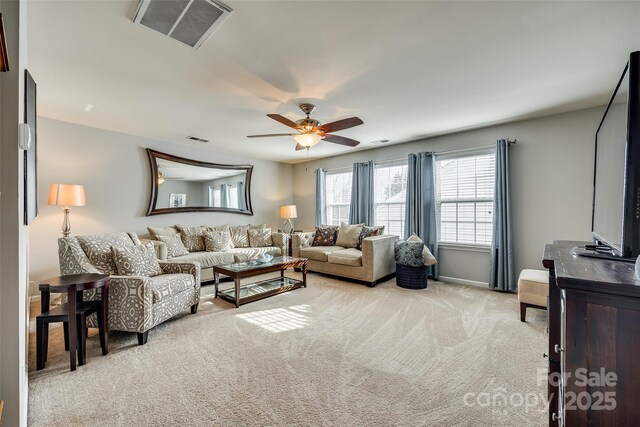 living area featuring a ceiling fan, visible vents, and light carpet