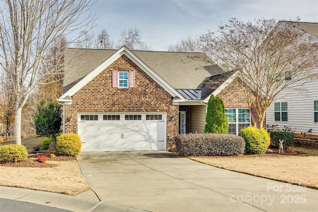 traditional-style home with driveway, a garage, a shingled roof, a standing seam roof, and brick siding