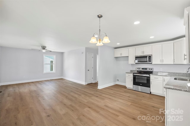 kitchen with appliances with stainless steel finishes, white cabinetry, sink, hanging light fixtures, and light wood-type flooring