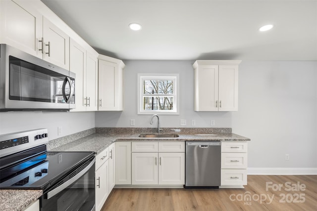 kitchen with white cabinetry, appliances with stainless steel finishes, sink, and light hardwood / wood-style flooring