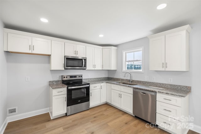 kitchen featuring stainless steel appliances, white cabinetry, sink, and light wood-type flooring