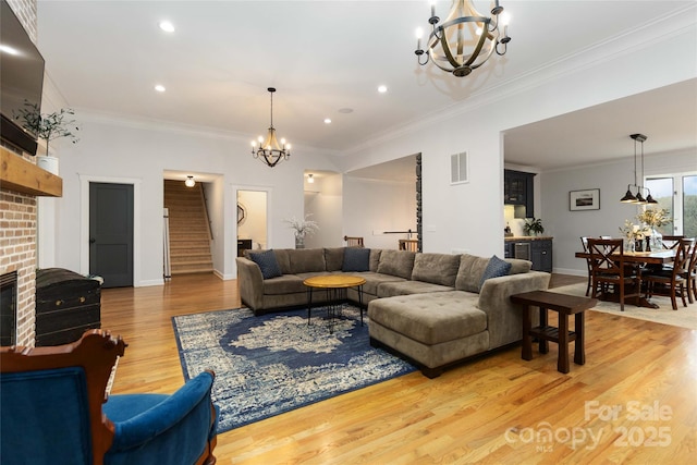 living room featuring an inviting chandelier, wood-type flooring, a fireplace, and crown molding