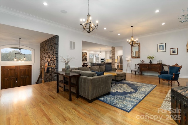 living room with an inviting chandelier, crown molding, plenty of natural light, and light hardwood / wood-style floors