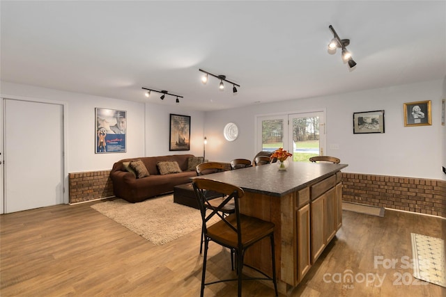 kitchen featuring hardwood / wood-style floors, a breakfast bar area, brick wall, and a kitchen island