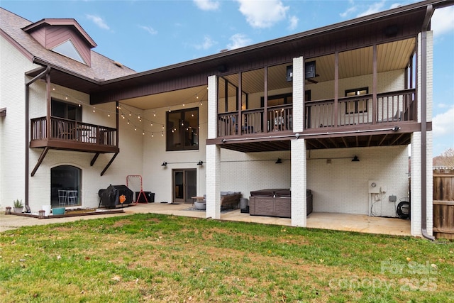 back of house with a balcony, a yard, a hot tub, and a patio area