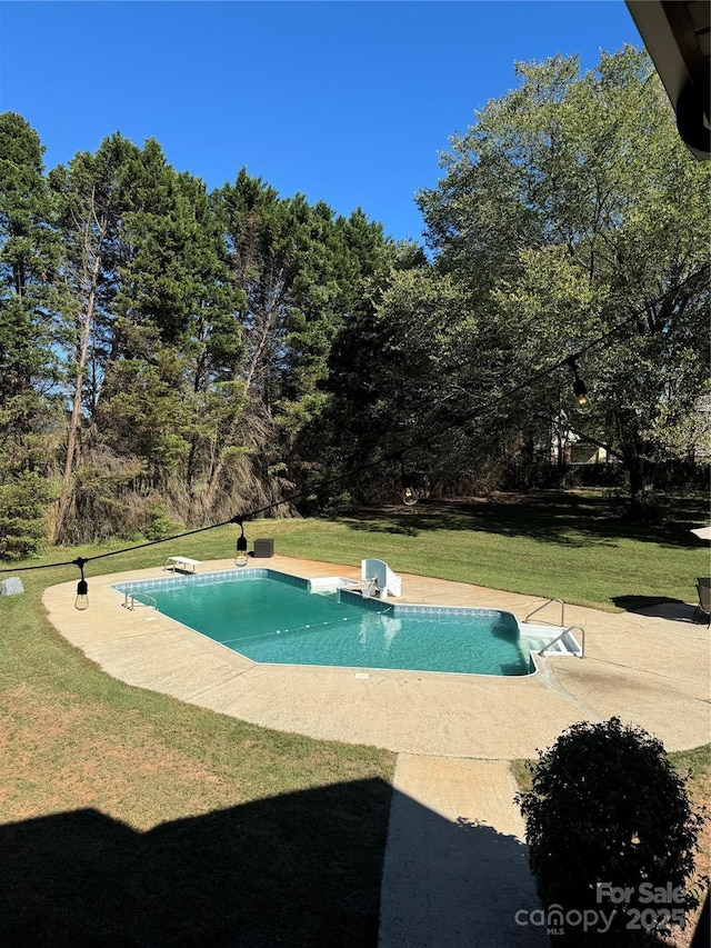 view of swimming pool featuring a yard, a diving board, and a patio area