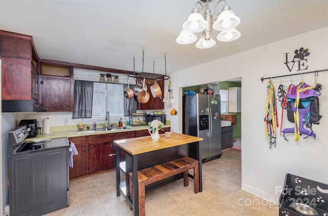 kitchen with pendant lighting, sink, electric range, stainless steel fridge, and a notable chandelier