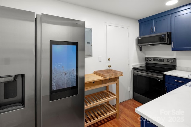 kitchen featuring black range with electric stovetop, blue cabinetry, electric panel, and light hardwood / wood-style flooring